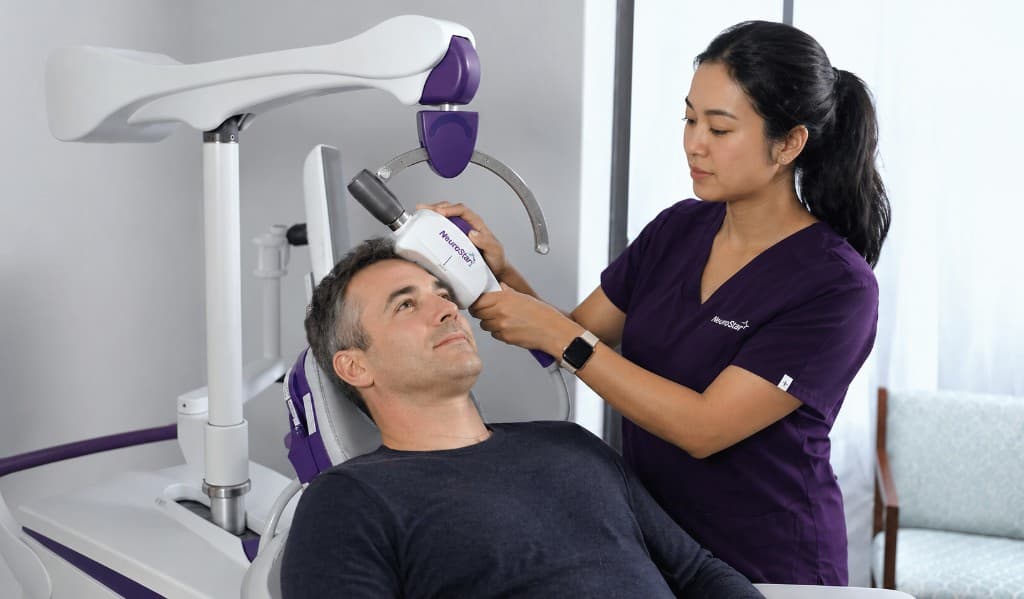 A patient seated calmly during a TMS treatment session